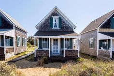 three beach cottages with green shutters and white trim on the windows, one in front of the other