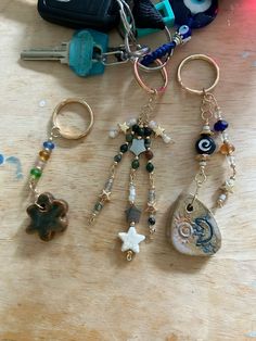 several different key chains with charms attached to them on top of a wooden table next to other items