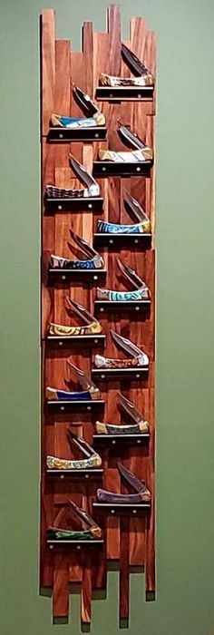 a wooden rack with many pairs of shoes hanging on it's sides in front of a green wall