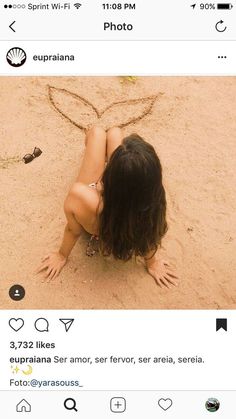 a woman laying in the sand with her back to the camera and writing on it