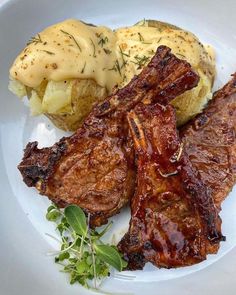 steak, potatoes and gravy on a white plate with green garnish