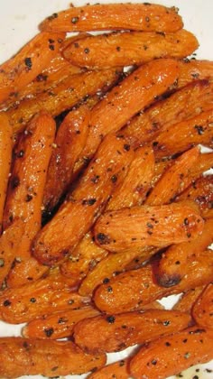 cooked carrots on a white plate with seasoning sprinkled around the edges