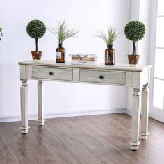 three potted plants sit on top of a white table in front of a window