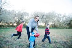 a woman and two boys playing with a football