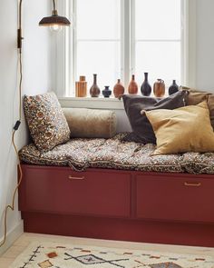 a window seat with pillows and vases on it