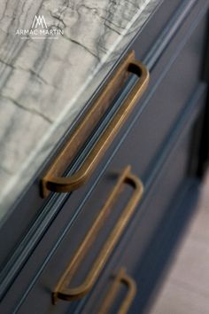 a close up of a door handle on a cabinet with a marble wall in the background