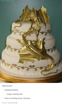 a white and gold wedding cake with a dragon on top