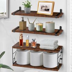 two shelves with towels, candles and other items on them next to a potted plant