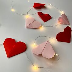 origami hearts and lights on a white surface