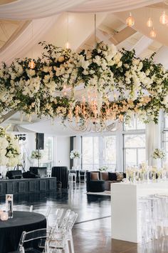 a room filled with lots of white flowers and chandelier hanging from the ceiling