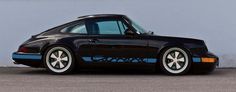 a black and red porsche parked in front of a white wall with graffiti on it