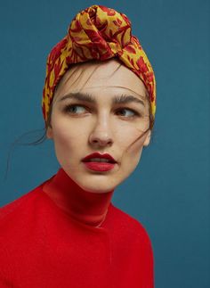 a woman with red lipstick and a yellow head scarf on her head is looking at the camera