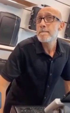 an older man sitting in front of a laptop computer with his hand on the keyboard