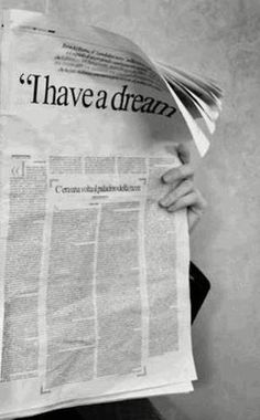 a person holding up a newspaper with the words i have a dream written on it