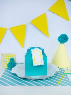 a blue and yellow birthday party with paper hats, gift bags, and tissue pom poms