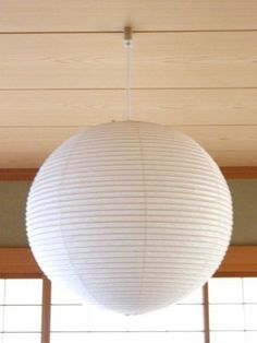 a white lamp hanging from the ceiling in a room with wood paneling and windows