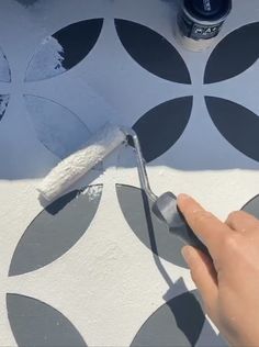 someone using a paint roller to paint a wall with black and white circles on it