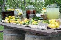 lemons and limeade are on display at an outdoor party with mason jars filled with lemon juice