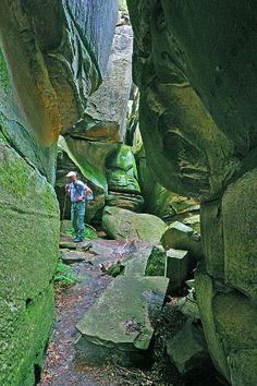 a man is standing in the middle of a narrow canyon with rocks and moss growing on both sides