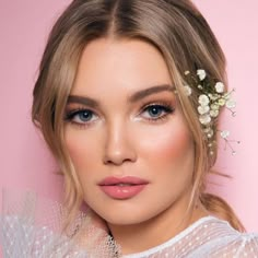 a woman with blonde hair and blue eyes wearing a flower in her hair is looking at the camera