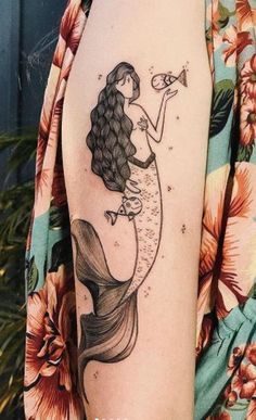 a woman with a tattoo on her arm is holding a trumpet in her right hand