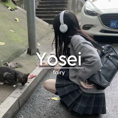 a woman kneeling down next to a black and white cat with headphones in her ears