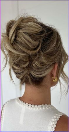 a woman with blonde hair in a messy updo is shown from the back view