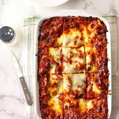 a square casserole dish filled with meat and cheese on top of a table