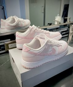 a pair of pink nike shoes sitting on top of a white box in front of a mirror