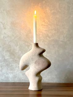 a white candle holder sitting on top of a wooden table