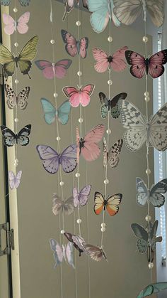 a mobile made out of butterflies is hanging from the ceiling in front of a window