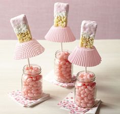 three jars filled with candy and marshmallows sitting on top of a table