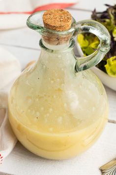 a glass bottle filled with liquid next to a salad