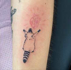 a small tattoo on the arm of a person with a raccoon holding a flower