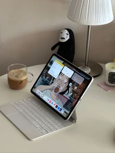 an open laptop computer sitting on top of a white desk next to a cup of coffee