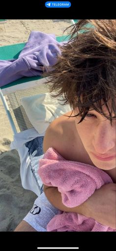 a woman sitting on top of a beach next to a towel