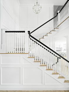 a white staircase with glass balconies and black handrails in a house