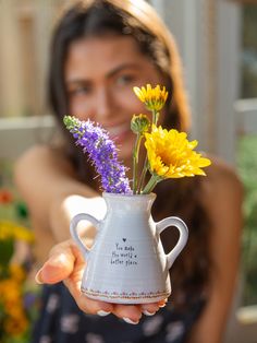 a woman holding a vase with flowers in it