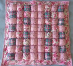 a pink and green blanket with many squares on the bottom one is made out of rolled up baby blankets