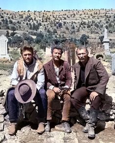 three men sitting on top of a stone slab