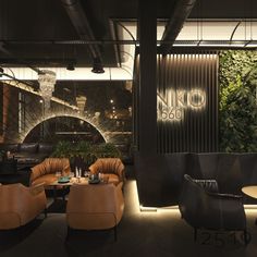 the interior of a modern restaurant with leather chairs and tables, plants on the wall