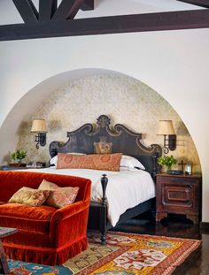 a large bed sitting next to a red chair in a bedroom