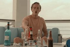 a man sitting at a table with bottles on top of it and an empty bottle in front of him