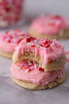 three cookies with pink frosting and sprinkles