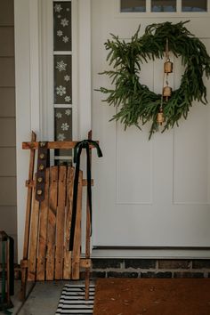 a wooden sled sitting in front of a white door with a wreath on it