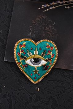 a heart shaped brooch with an evil eye on it's center, surrounded by other items