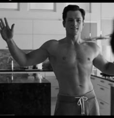 a shirtless man is standing in the kitchen with his hands out to someone else