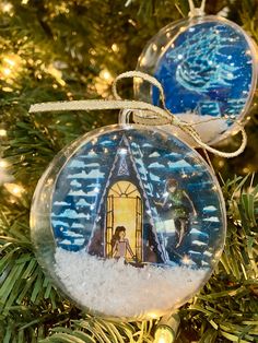 an ornament hanging from a christmas tree decorated with nativity scene and lights