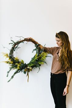 a woman is holding a wreath made out of branches