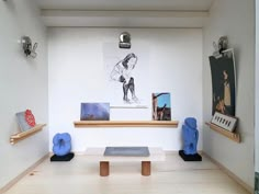 an art gallery with blue sculptures and pictures on the wall above them, along with bookshelves